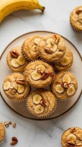 Top-down image of Air Fryer Banana Muffins served on a plate. The muffins are golden brown, moist, and fluffy.
